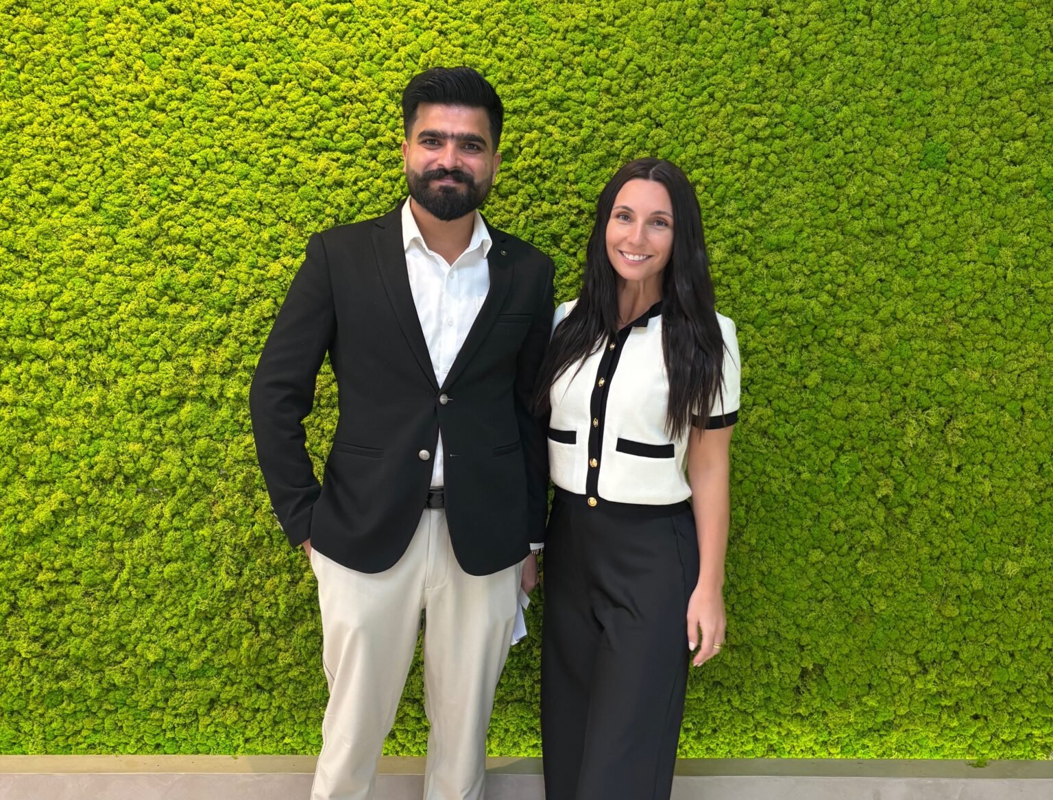 Business professionals posing together against a vibrant green moss wall, representing modern marketing and collaboration.